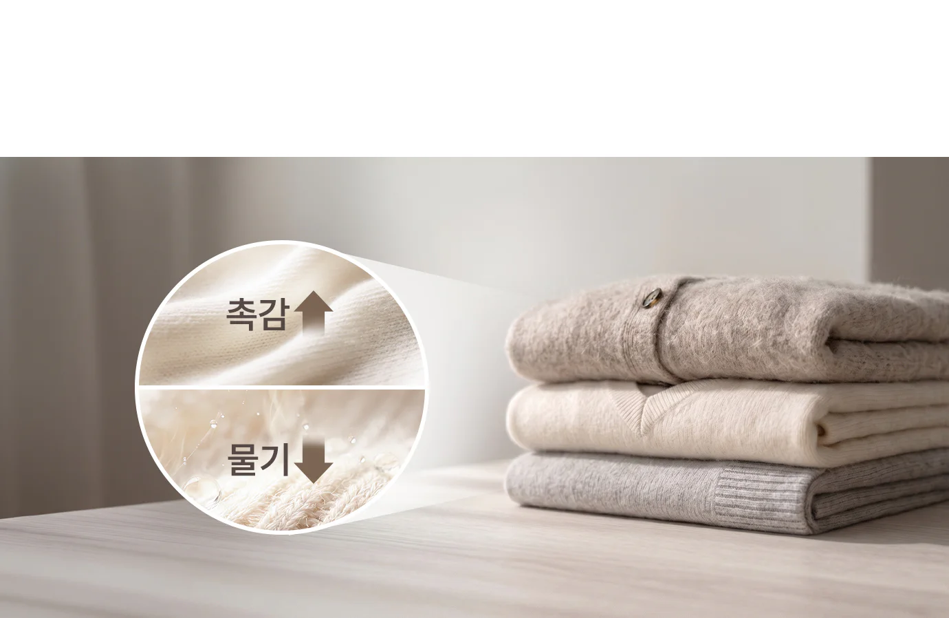 부드러운 질감의 니트들이 차곡차곡 쌓여 있으며, 위에서부터 크림색, 베이지색, 연회색, 짙은 회색 순으로 정렬되어 있습니다. 원형 도형안에 니트 질감을 클로즈업과 함께 촉감을 높이고 물기를 감소시킨다는 문구가 삽입되어 있습니다.